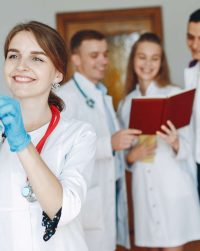 Men and women in hospital gowns study. Students practice medicine. Nurse with a syringe.